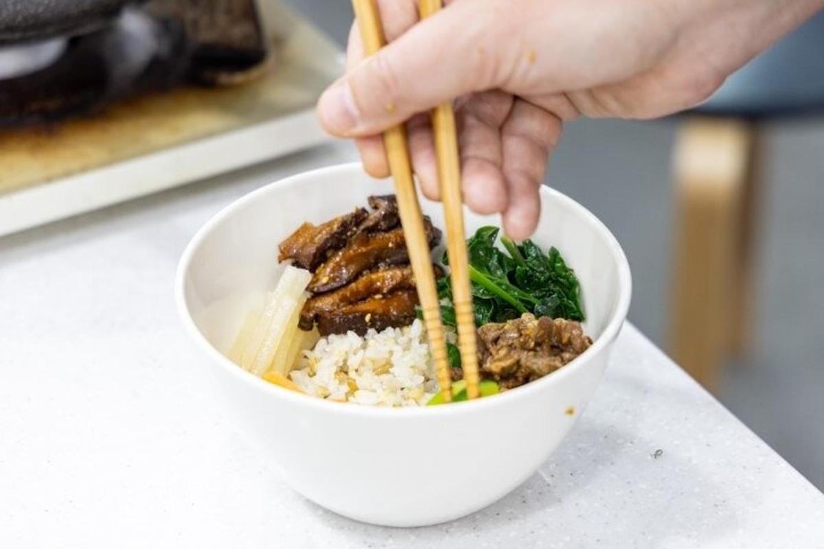 a person eating a bowl of food with chopsticks