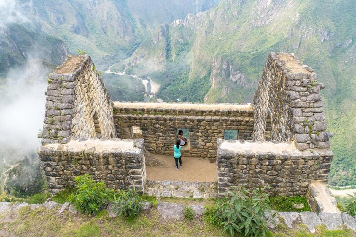 a woman standing in front of a stone building on a mountain