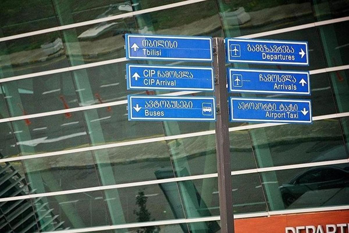 un stâlp cu indicatoare stradale albastre în fața unei clădiri