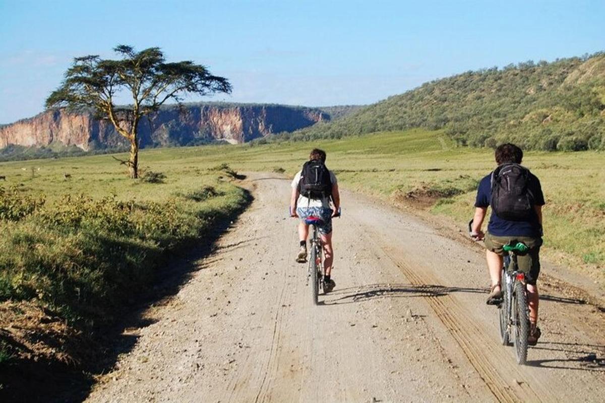 two people riding bikes down a dirt road