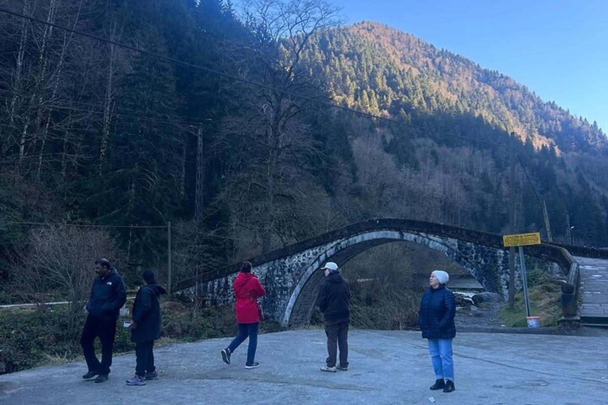 a group of people flying a kite over a bridge