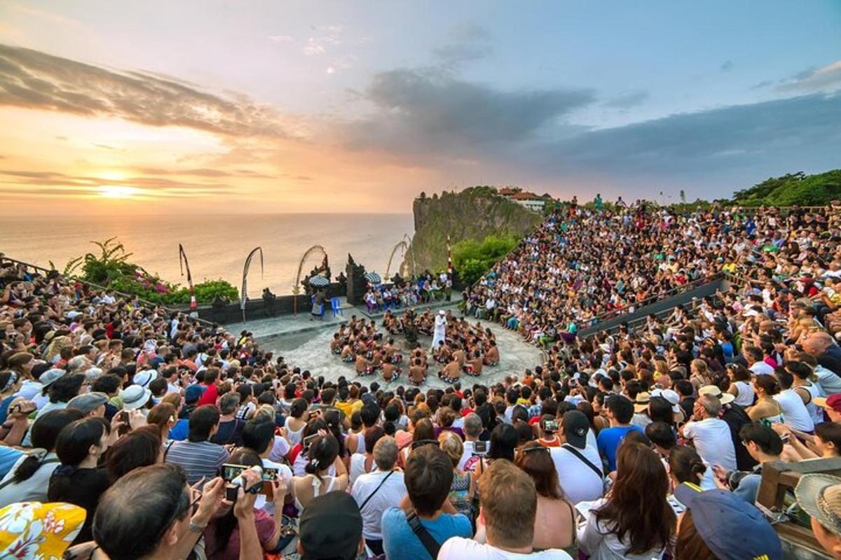 a large crowd of people watching a concert in front of the ocean