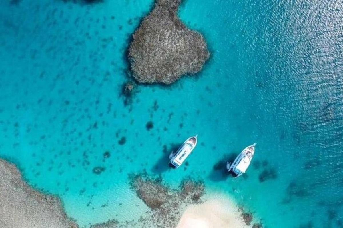 two boats in the water next to a island