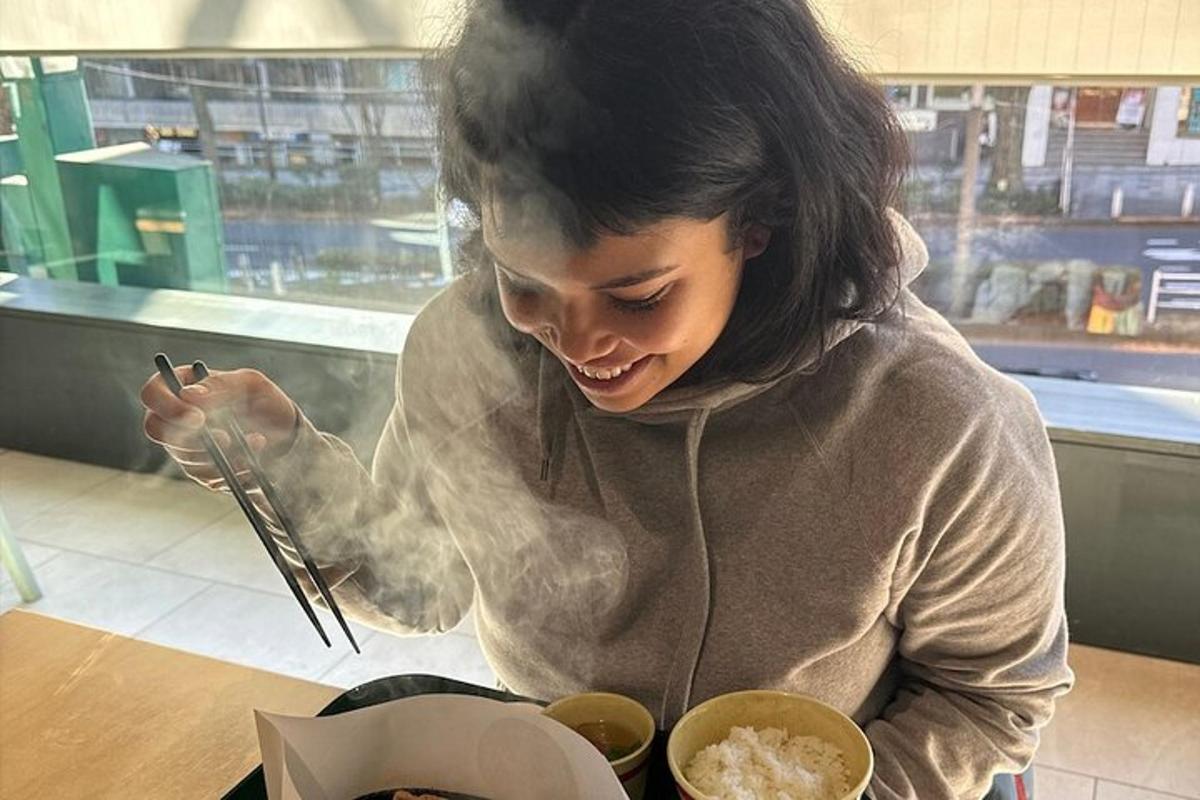 una donna seduta a un tavolo che mangia cibo con le bacchette