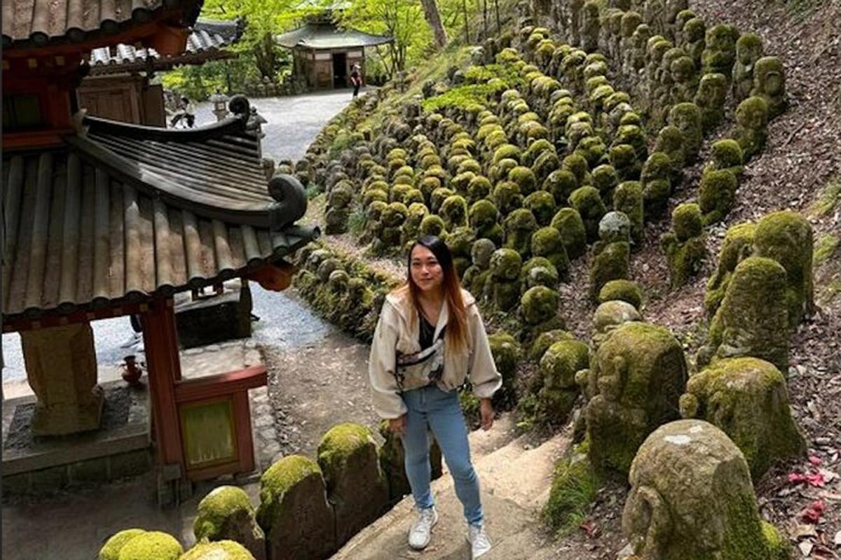 une femme debout à côté d'une rangée de buissons couverts de mousse