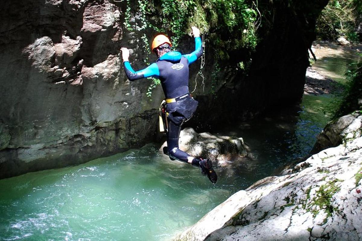 a person jumping into a river in a wetsuit
