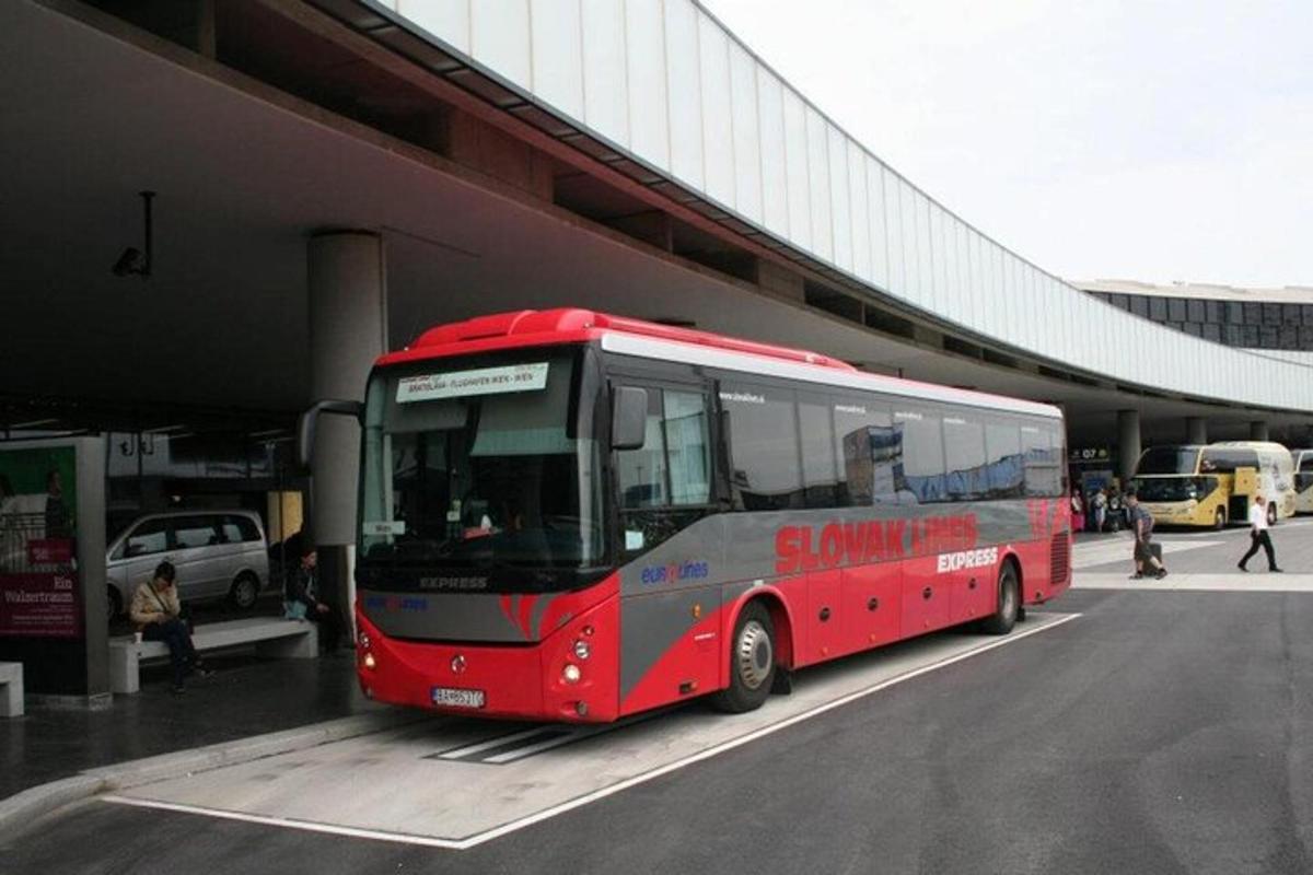 Egy piros busz parkol egy épület mellett