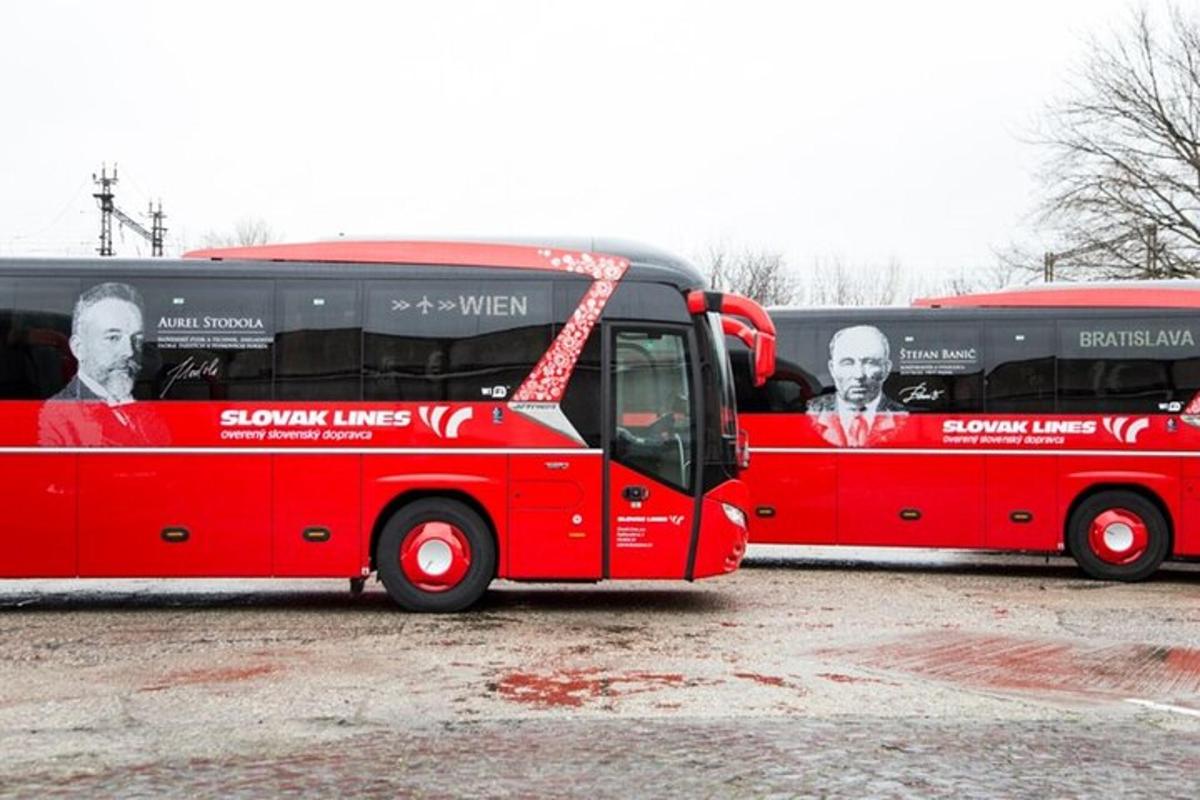 Két piros busz parkol egy parkolóban