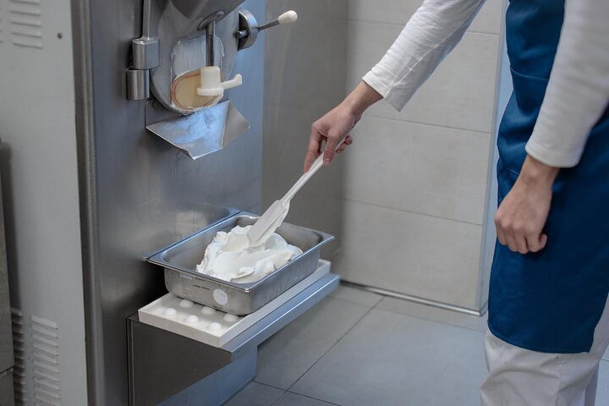una persona que sostiene una espátula en un recipiente con comida