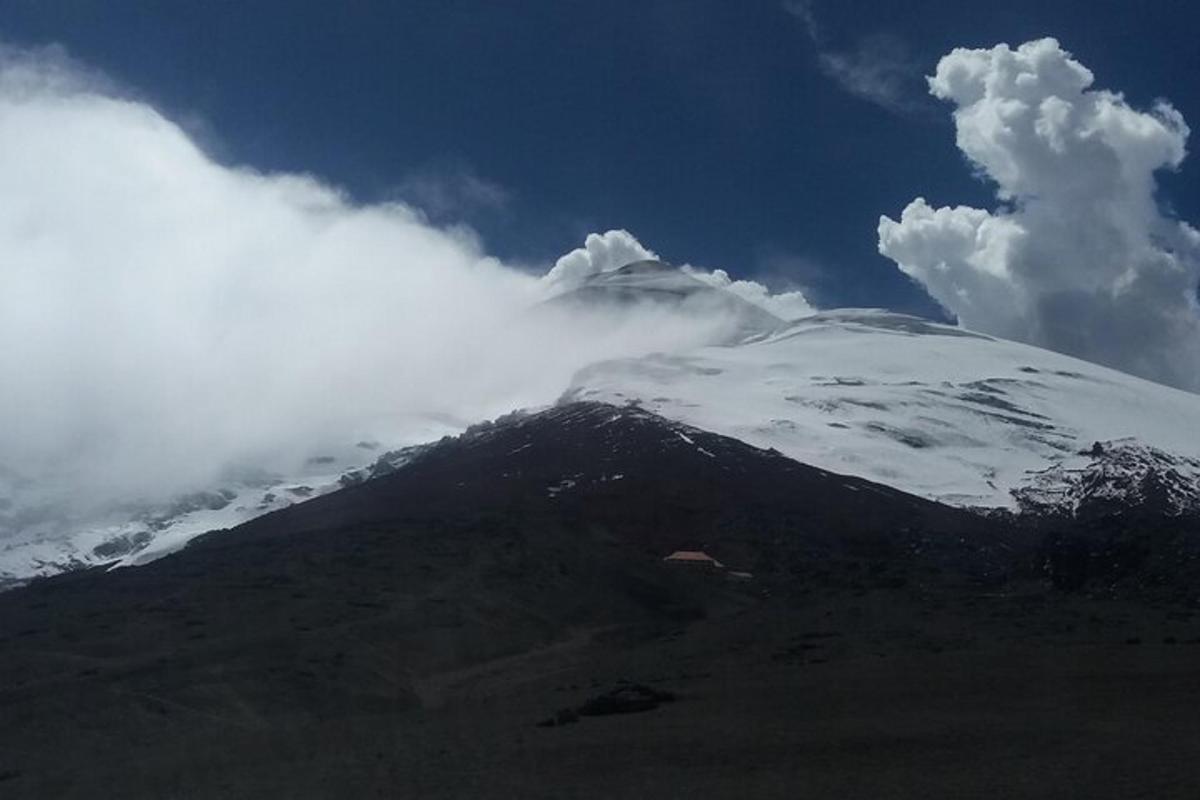 a snow covered mountain with clouds on top of it