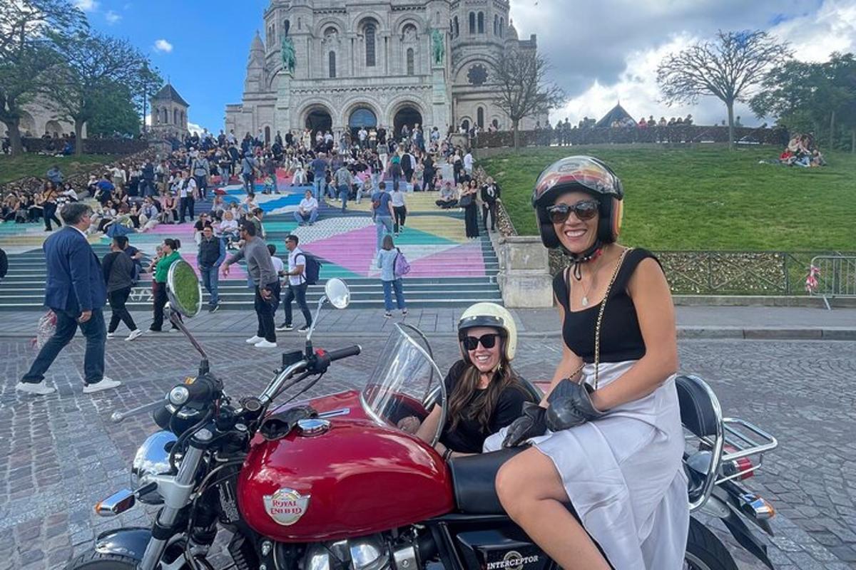 two women on a red motorcycle in front of a building