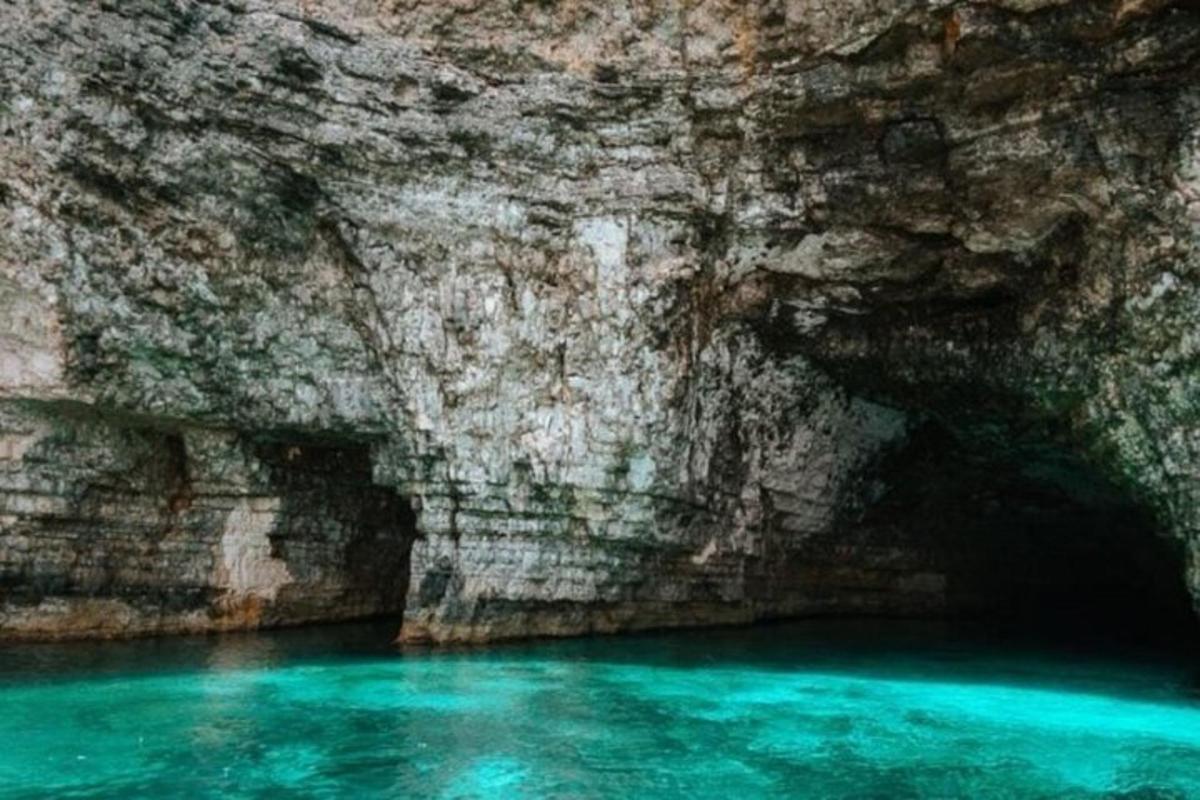 a cave with blue water in front of a rock wall