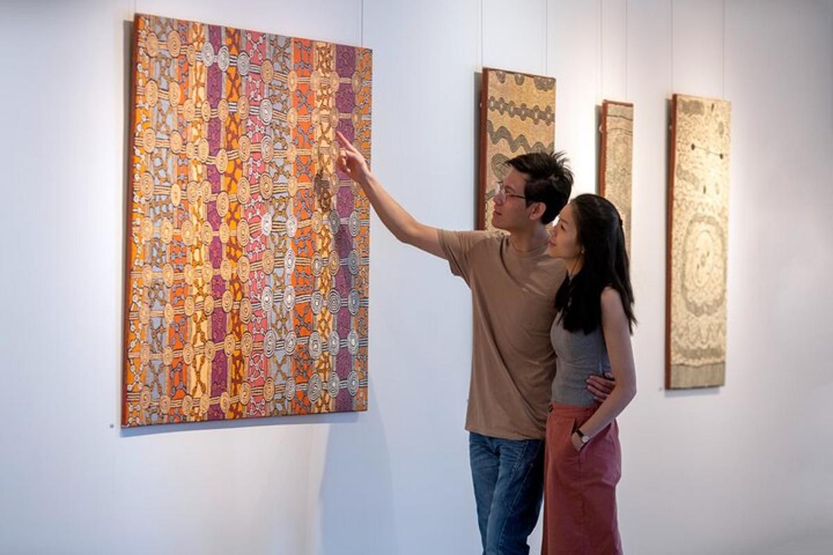 a man and a woman looking at a painting on a wall