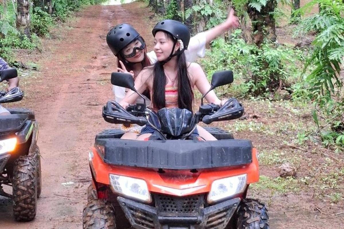 Dos chicas viajando en un vehículo de cuatro ruedas por un camino de tierra