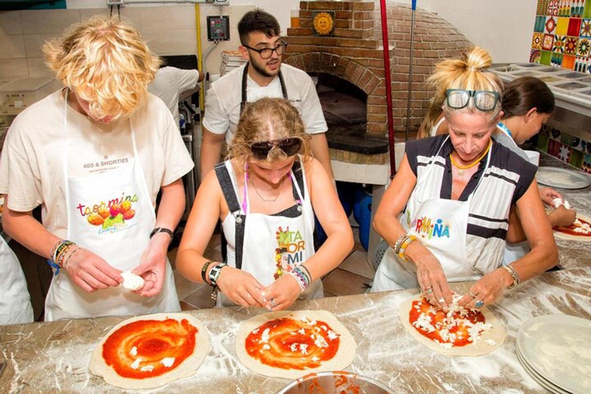 a group of people making pizzas in a kitchen