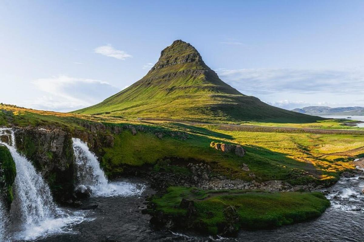 a waterfall and a mountain in the middle of a field