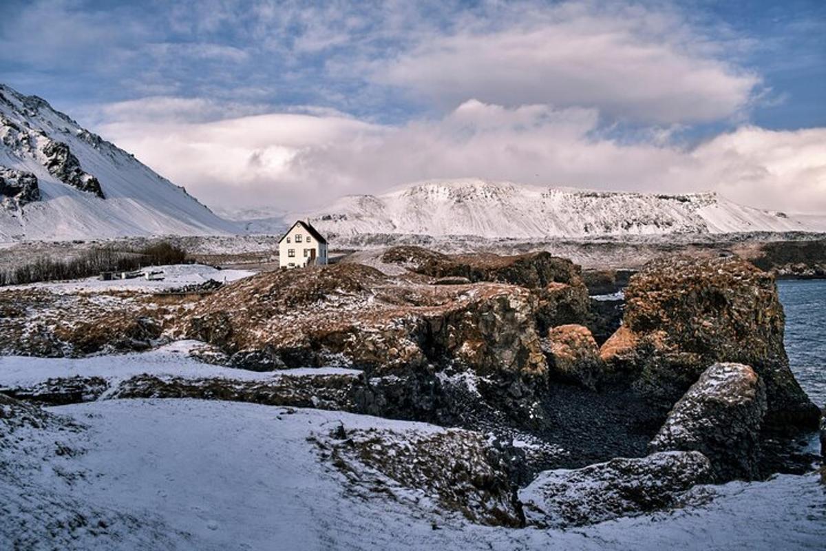a house on a snowy island with snow covered mountains