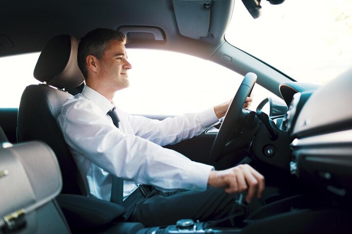 mies ajaa autoa kädet ohjauspyörällä