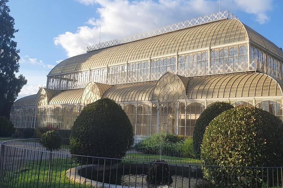 a large glass building with bushes in front of it