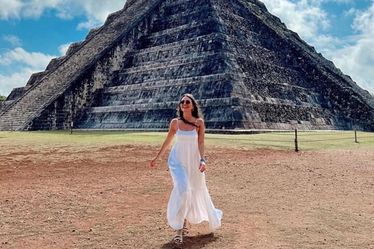 a woman in a white dress standing in front of a pyramid