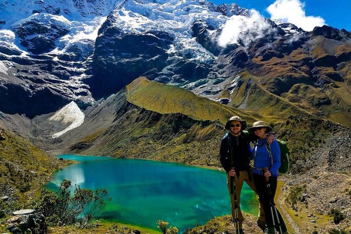 due persone in piedi sulla cima di una montagna con un lago