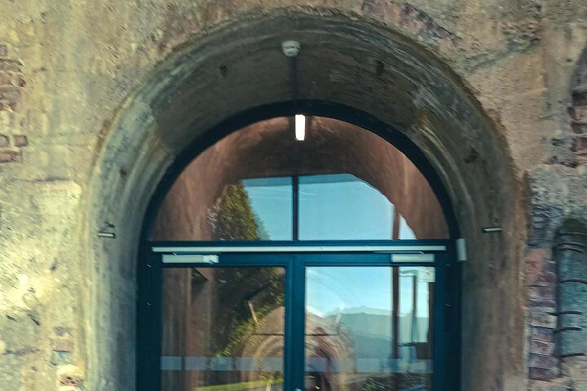 an arched window in a brick building with a reflection in it
