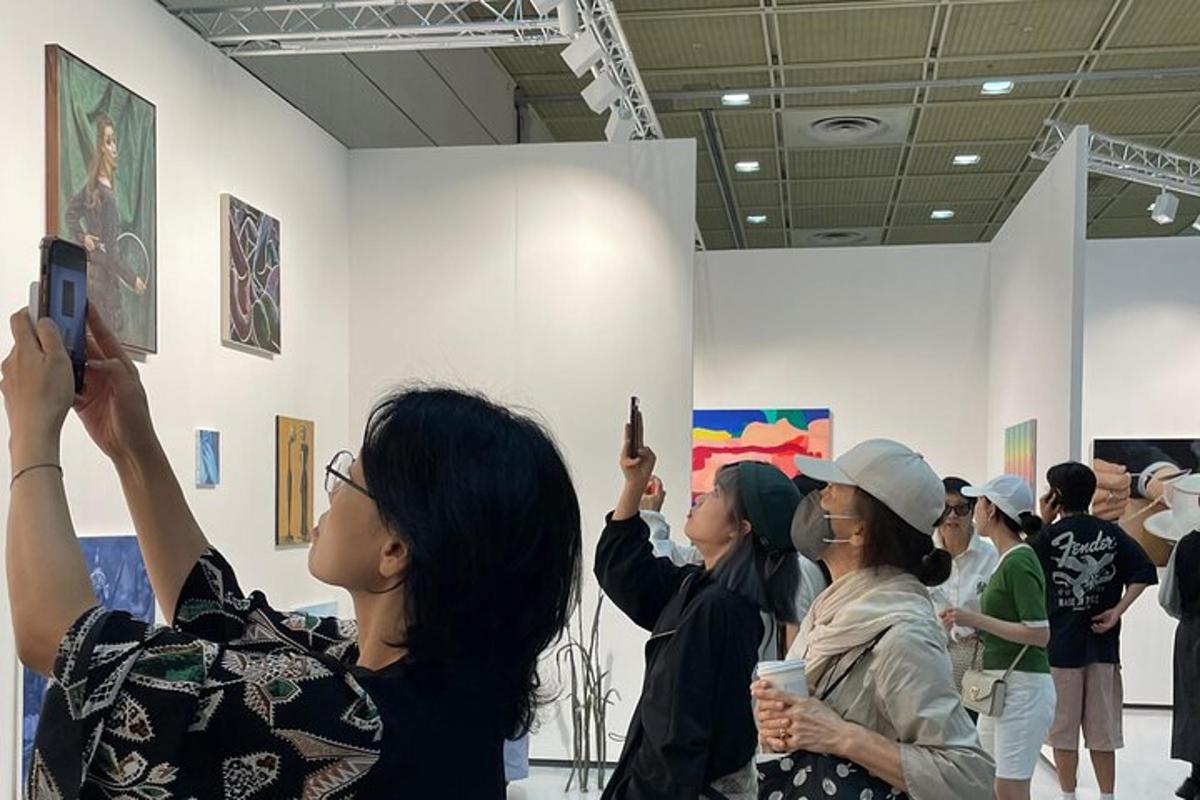 um grupo de pessoas tirando fotos de pinturas em um museu