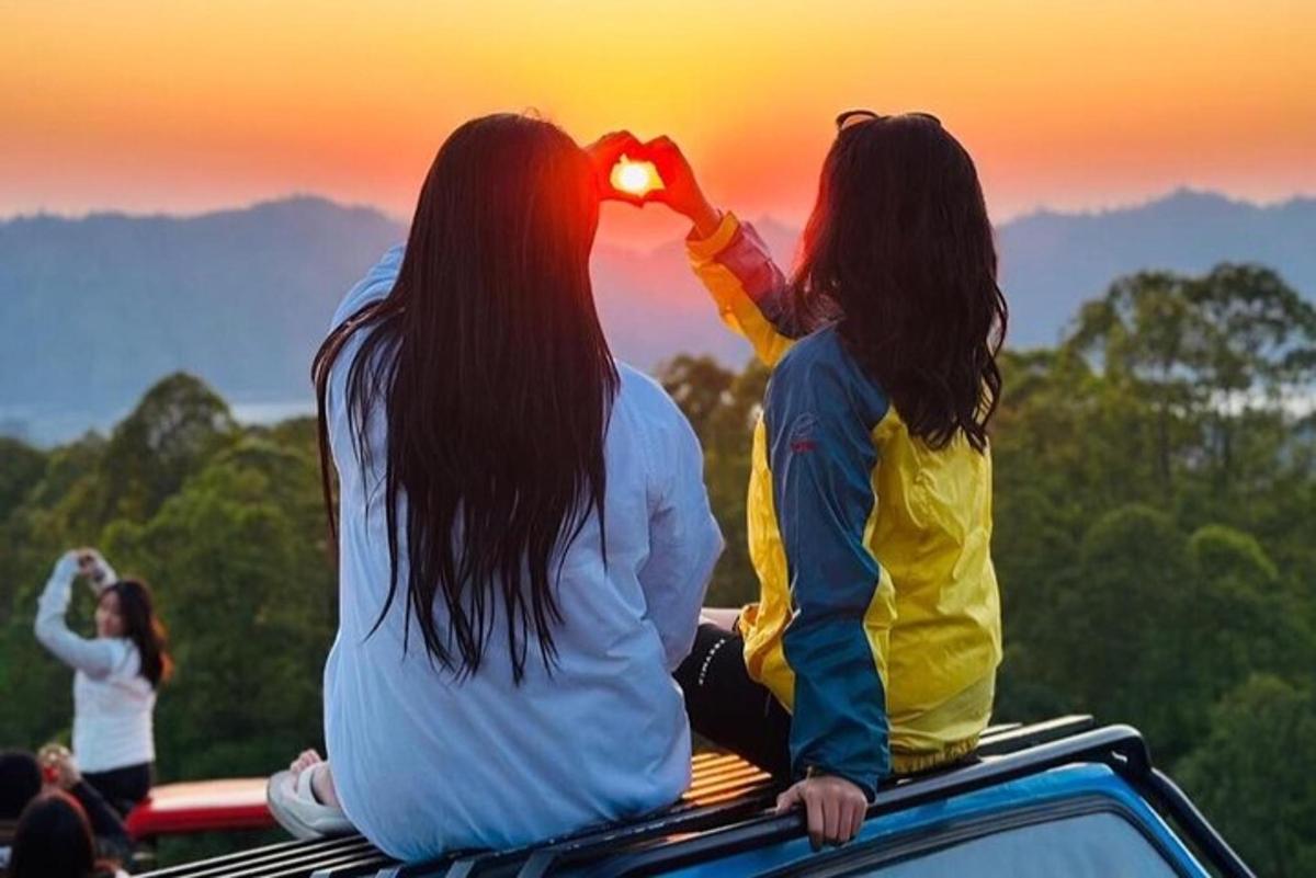 due donne sedute sul tetto di un camion che guardano il tramonto