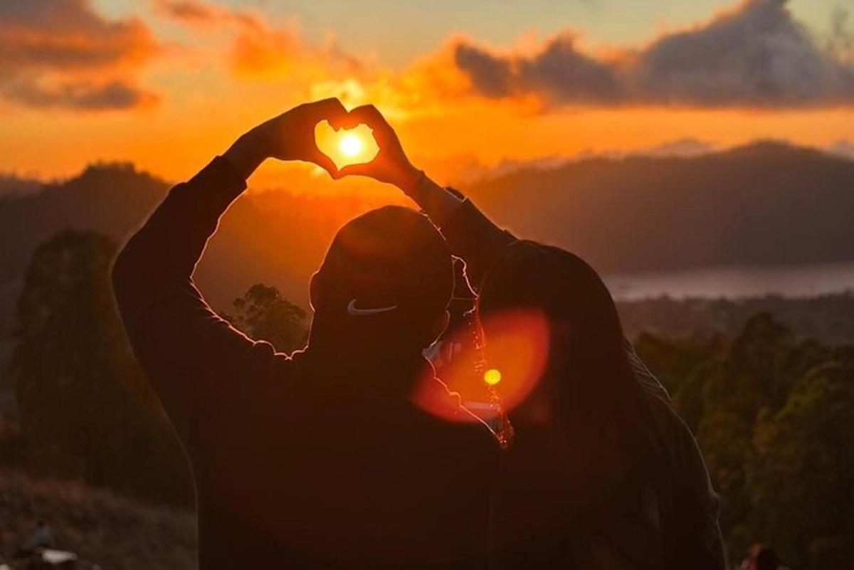 due persone che formano un cuore con il tramonto sullo sfondo
