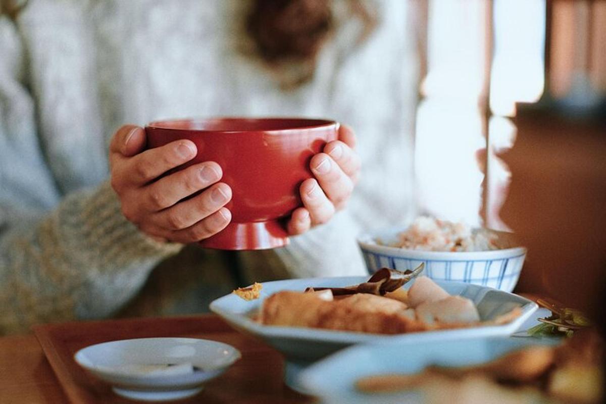 una persona che tiene una tazza rossa sopra un piatto di cibo