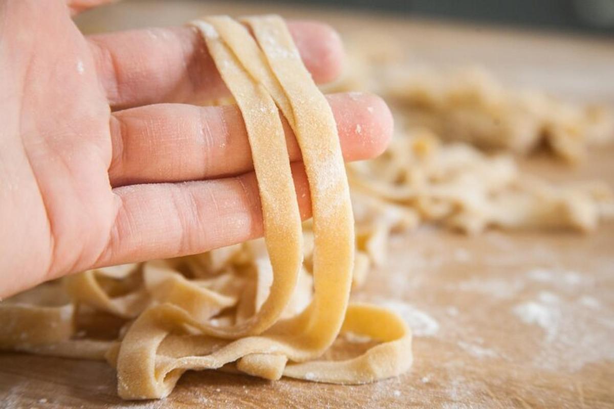 una mà que sosté un tros de menjar amb pasta