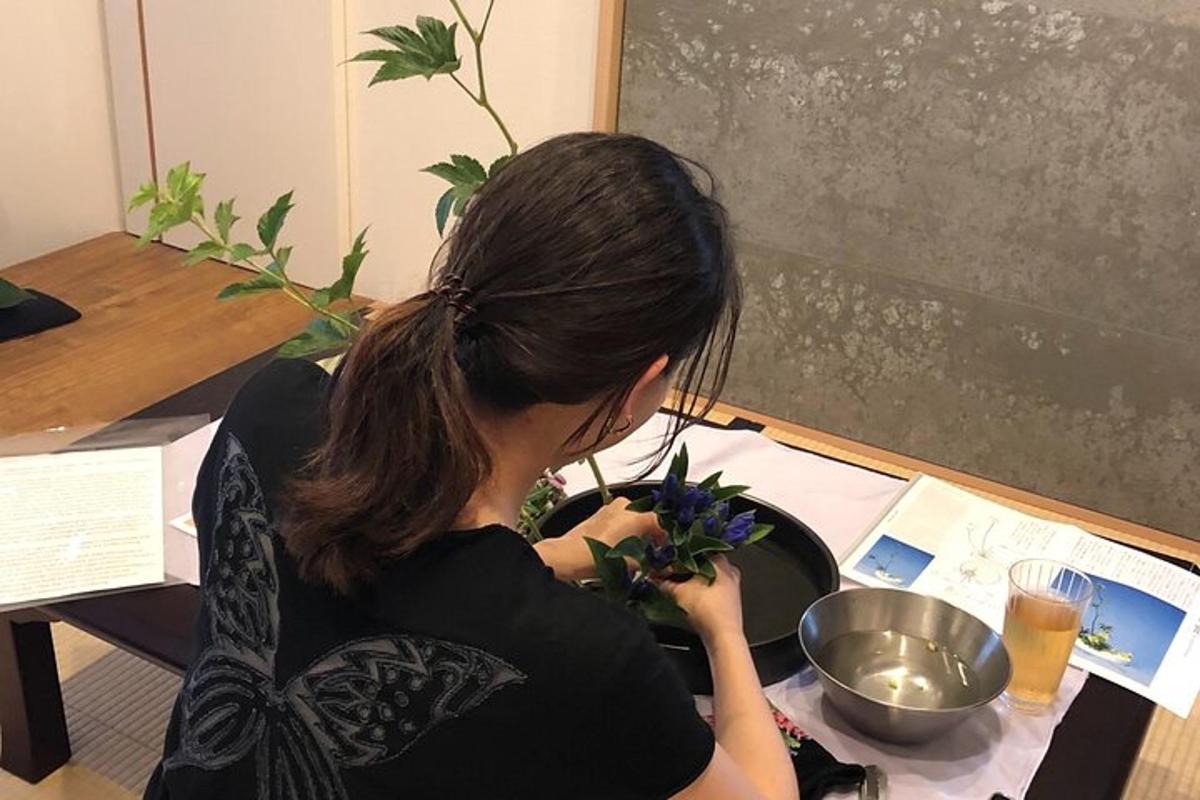 kona situr við borð og heldur á blómi