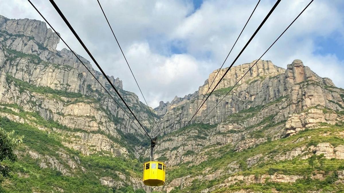 a yellow cable car in front of a mountain