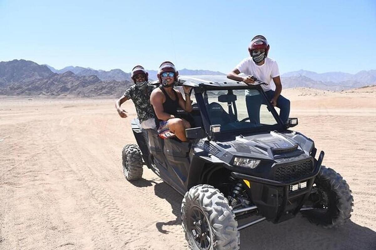 Tres personas sentadas en un vehículo todo terreno en el desierto
