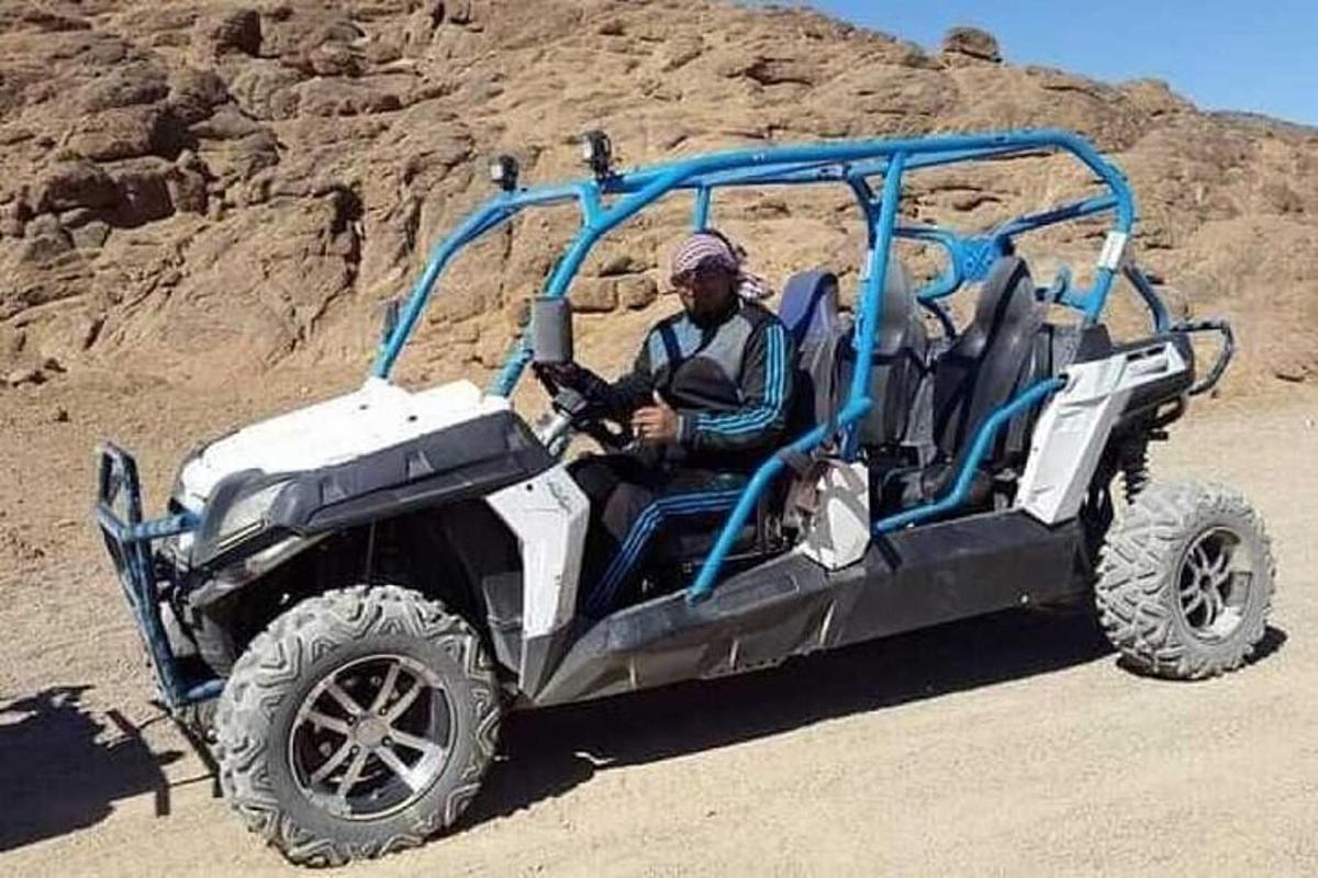 Un hombre sentado en un vehículo en el desierto.