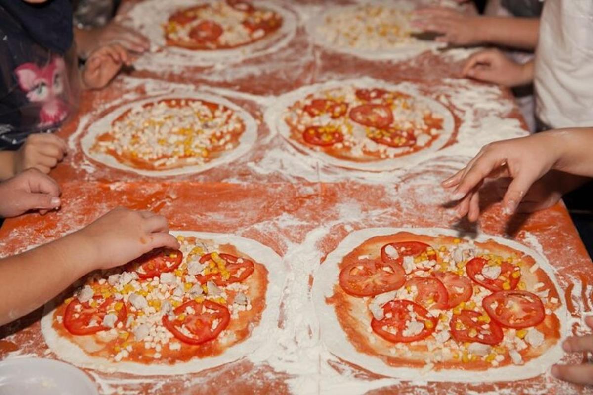 un grup de persones fent pizzes a la taula