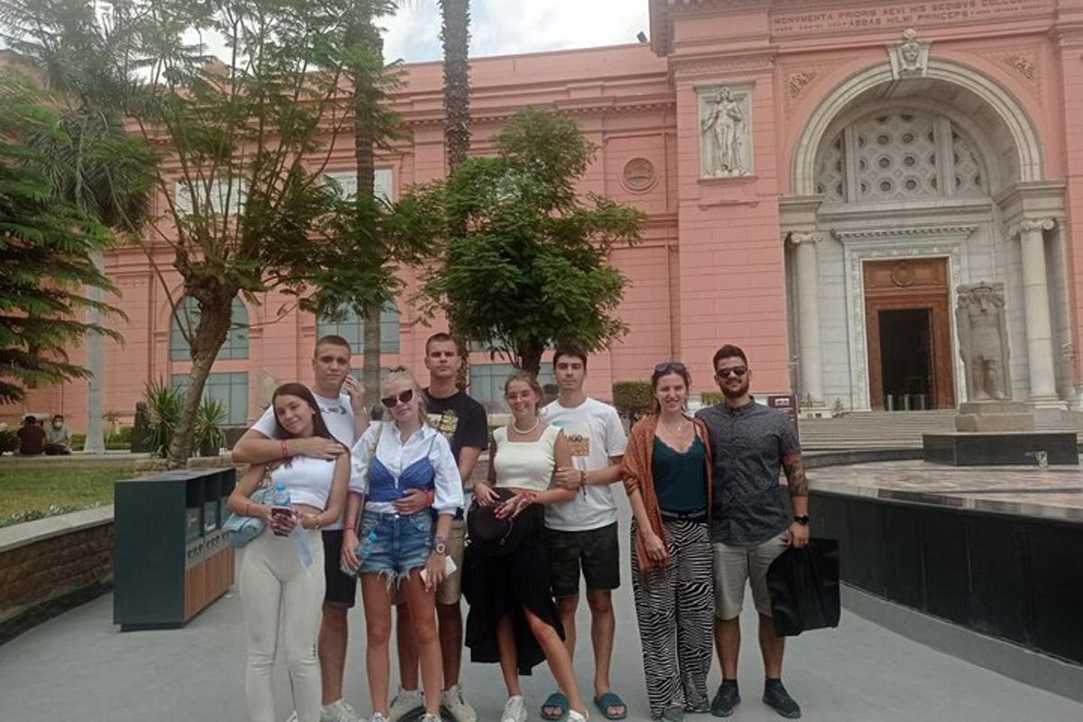 Un grupo de personas de pie frente a un edificio rosa.