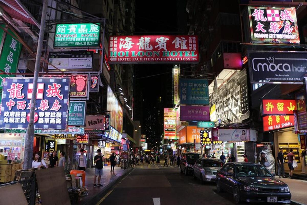 Una calle concurrida de la ciudad por la noche con letreros de neón.