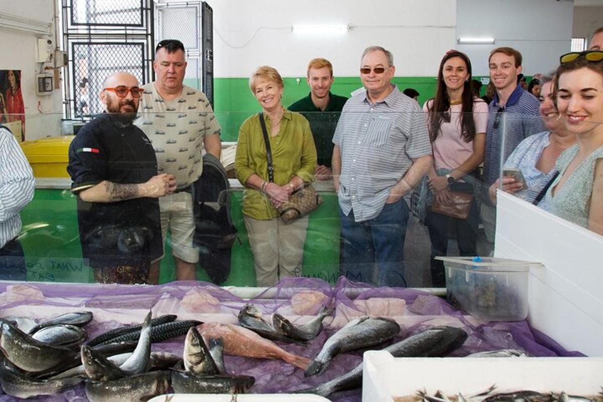 Un grupo de personas de pie frente a una mesa de pescado.