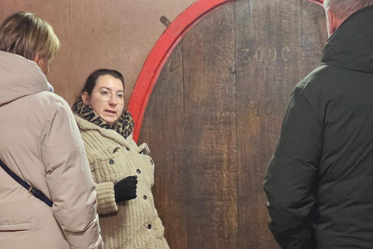 a woman standing in front of a wine barrel