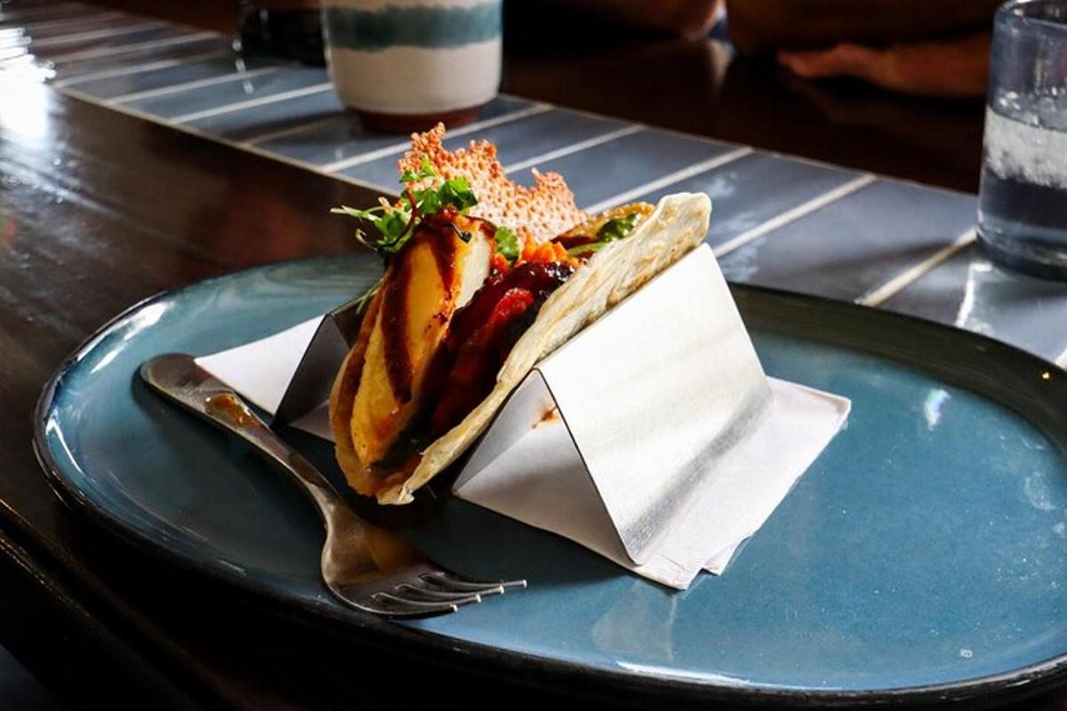 a hot dog on a blue plate with a fork and napkin
