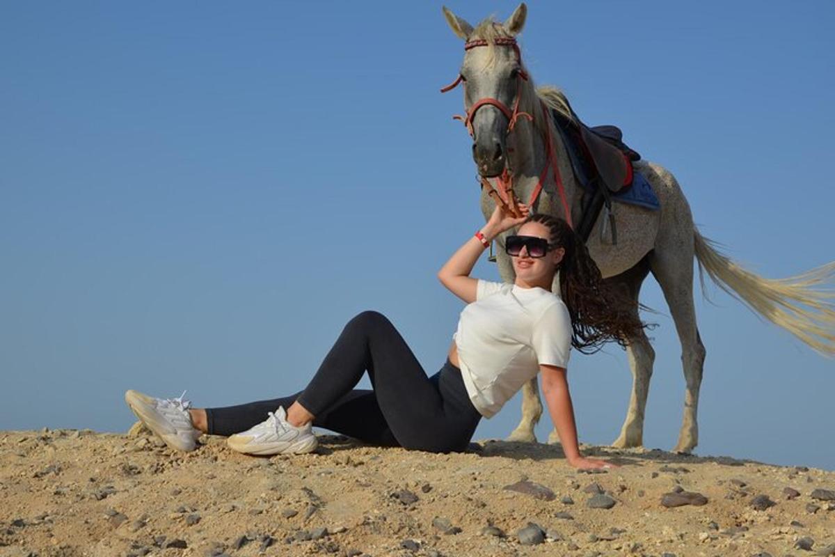 uma mulher sentada no chão com um cavalo