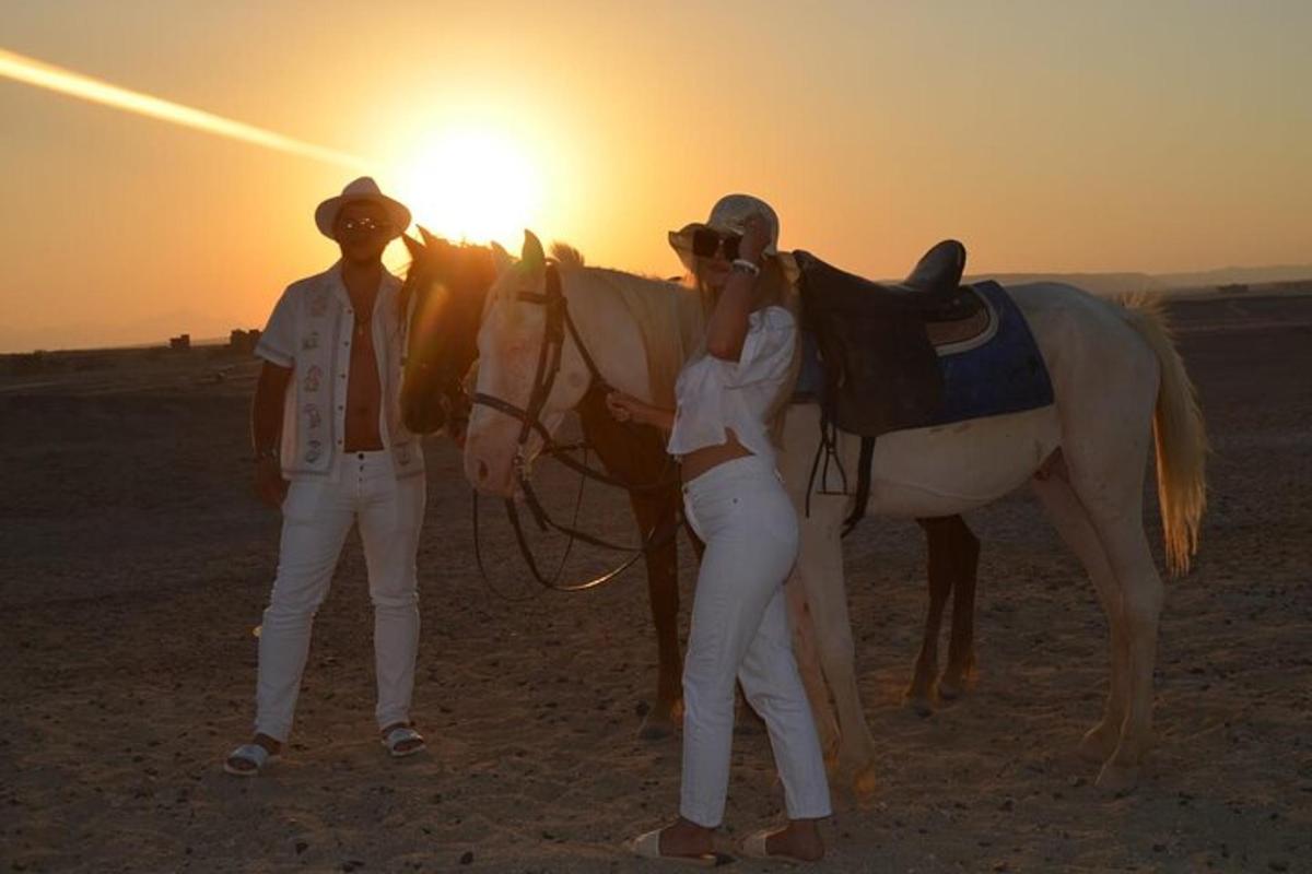 um homem e uma mulher em pé ao lado de um cavalo no deserto