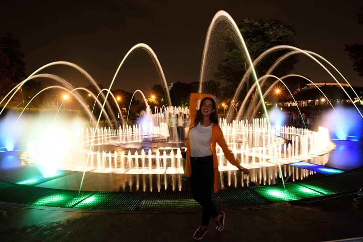 Una mujer parada frente a una fuente por la noche.