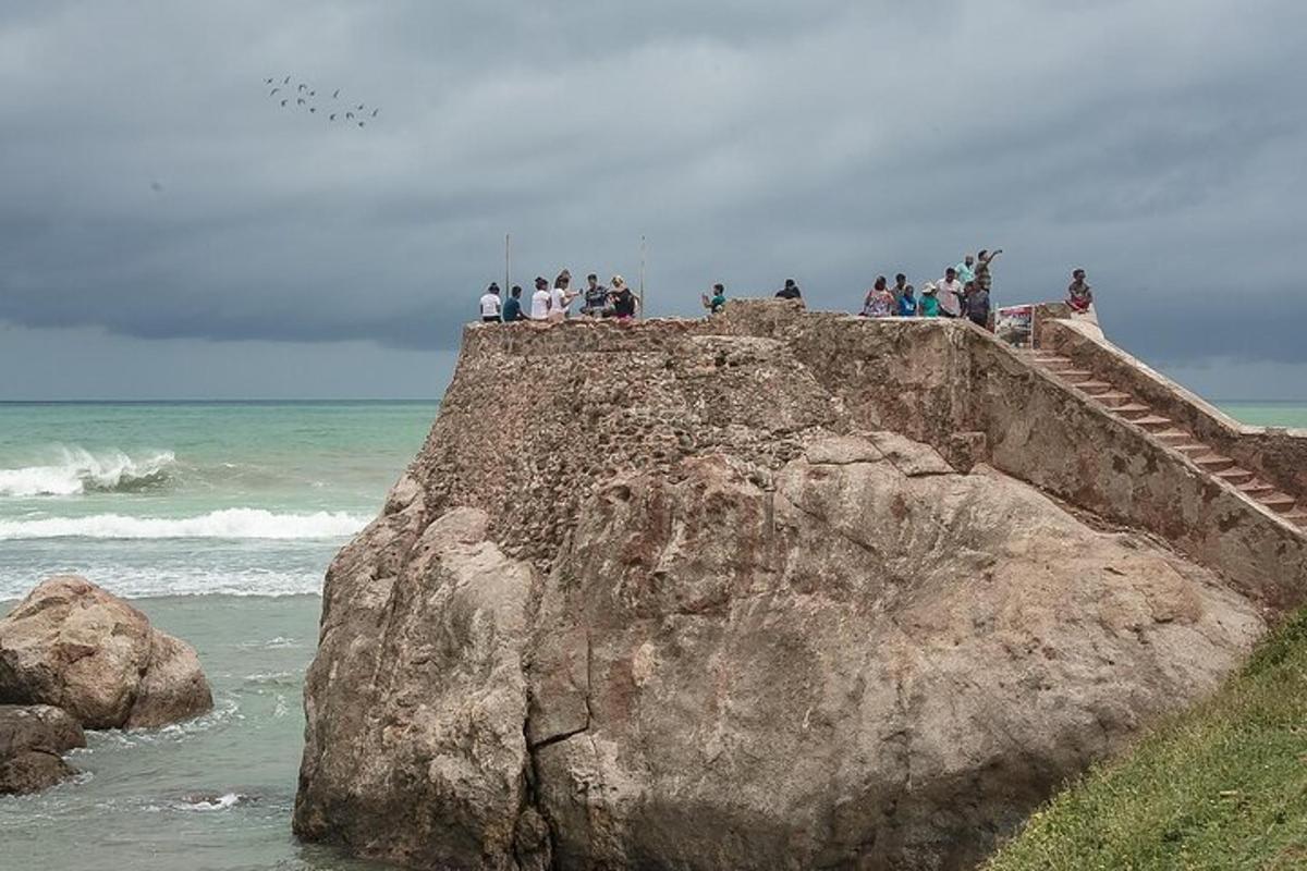 skupina lidí stojících na skále poblíž oceánu