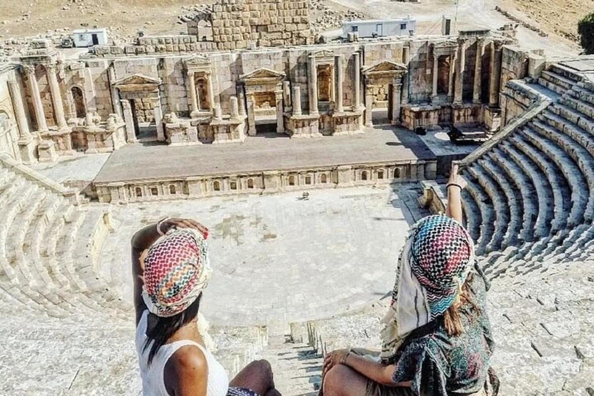 Dos personas sentadas en un anfiteatro con las manos en el aire.