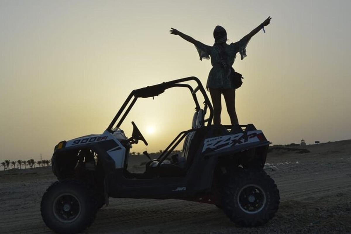 Una mujer parada encima de un vehículo en el desierto.