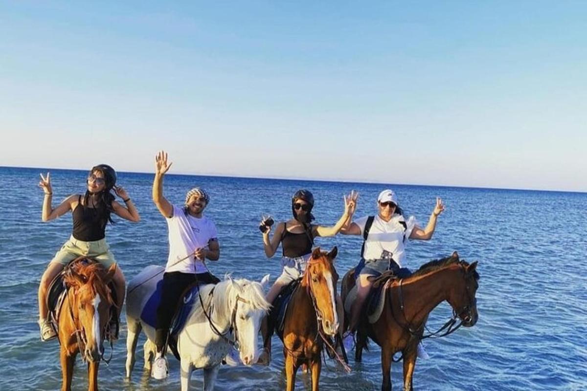 un grup de persones muntant a cavall a la platja