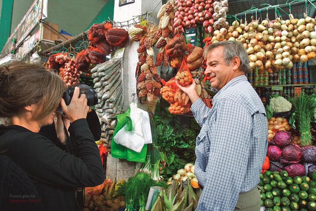 sieviete fotografē vīrieti augļu un dārzeņu tirgū