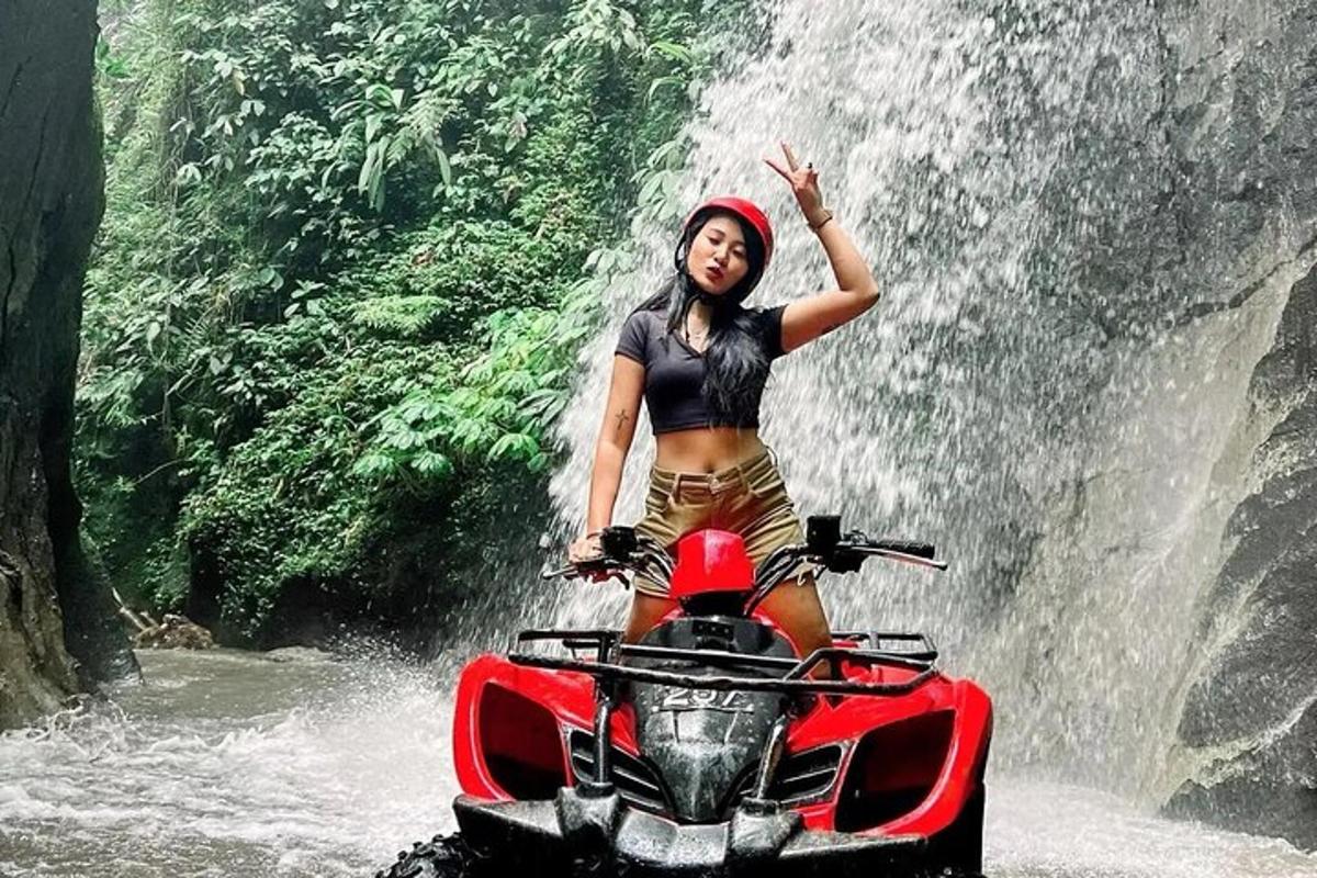 uma mulher parada em uma motocicleta em frente a uma cachoeira